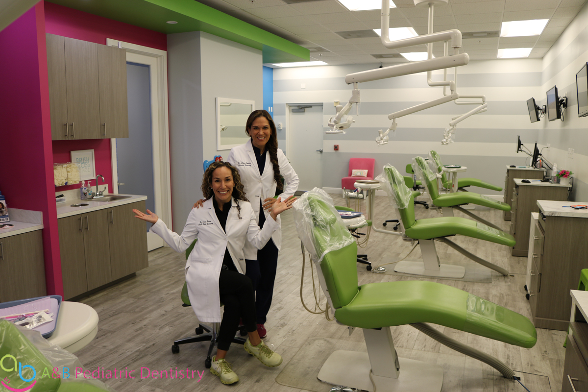 dr A and Dr B smiling in their main office dental chair area